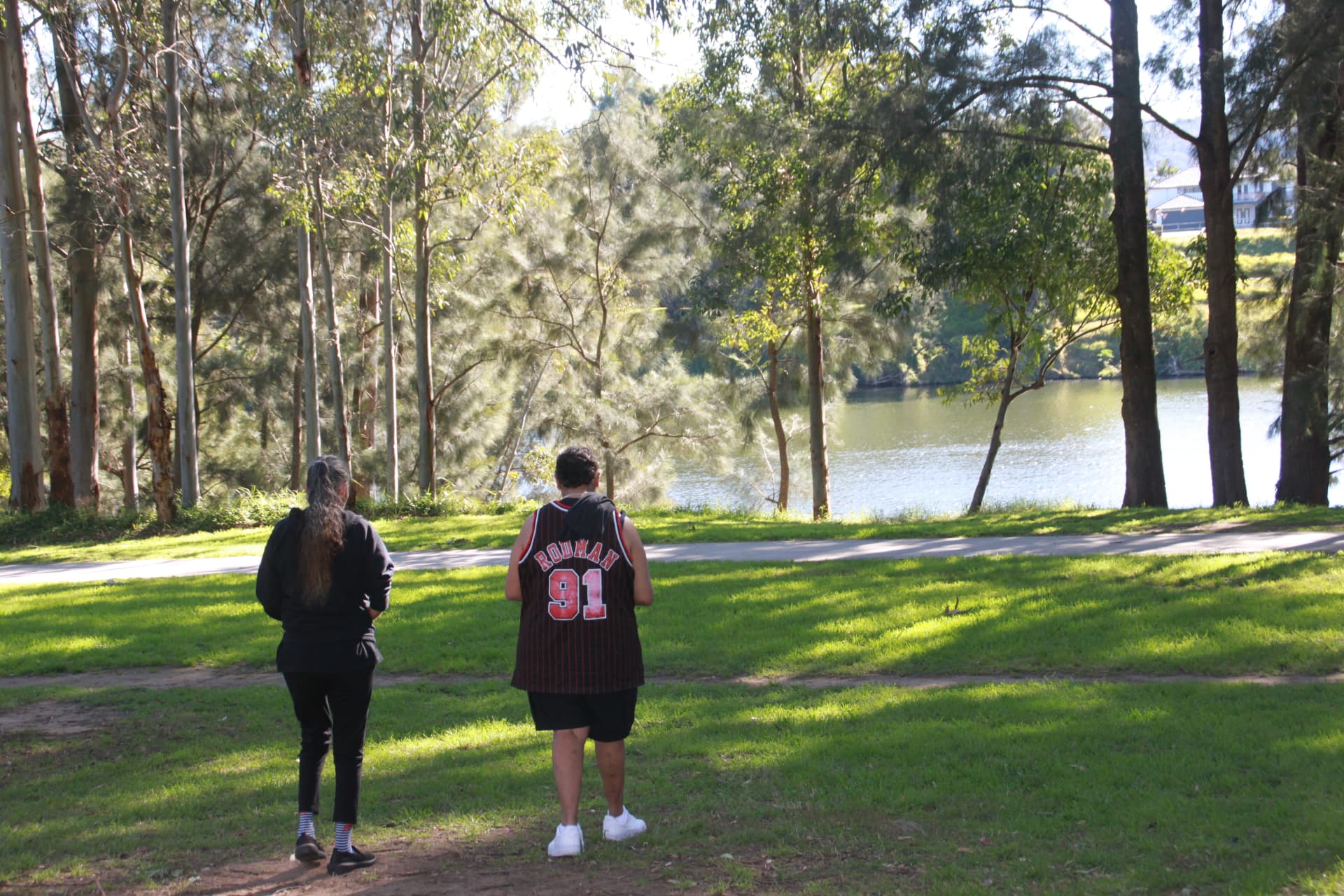 Support coordinator and participant walking together beside the river